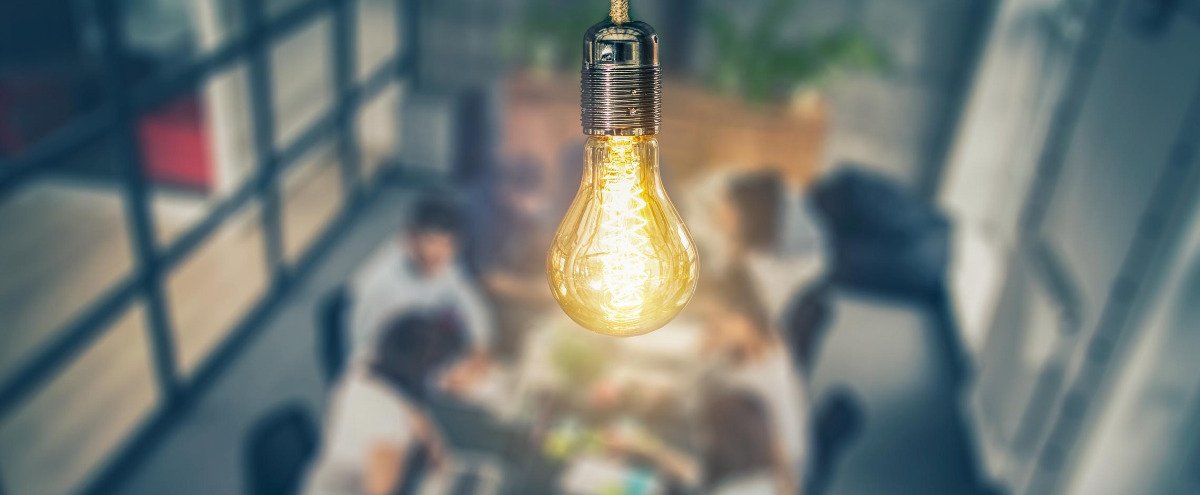 Close up of a light bulb with a meeting occuring behind it