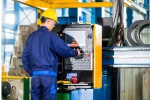 A working wearing a hard hat working on a factory machine