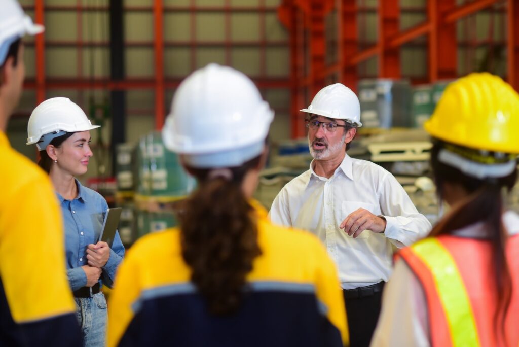 Construction manager wearing hardhat talking with other construction members